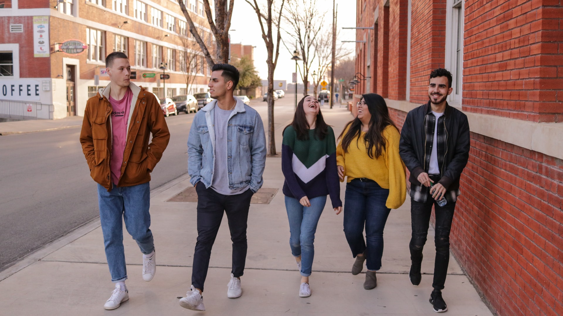 Group of young adults walking down the sidewalk together.