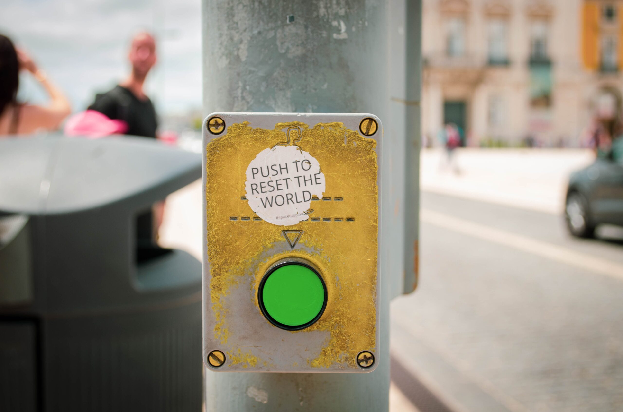 A green button on a pole that says, "push to reset the world".