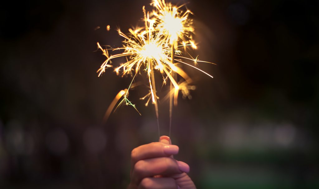 Person holding two sparklers.