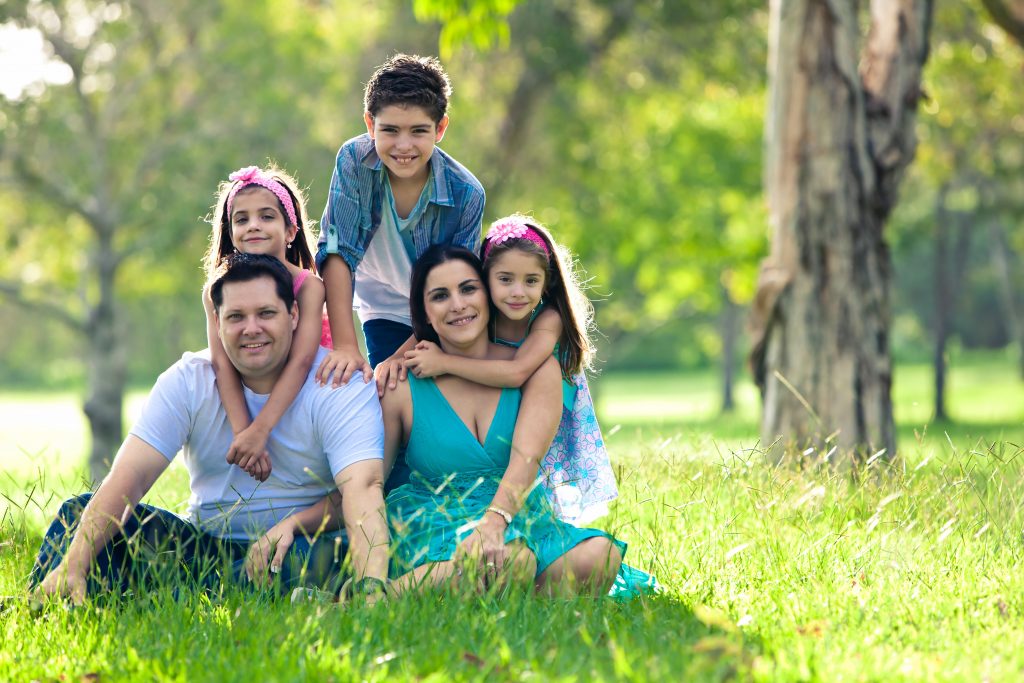 Family sitting together in grass and posing for a portrait.