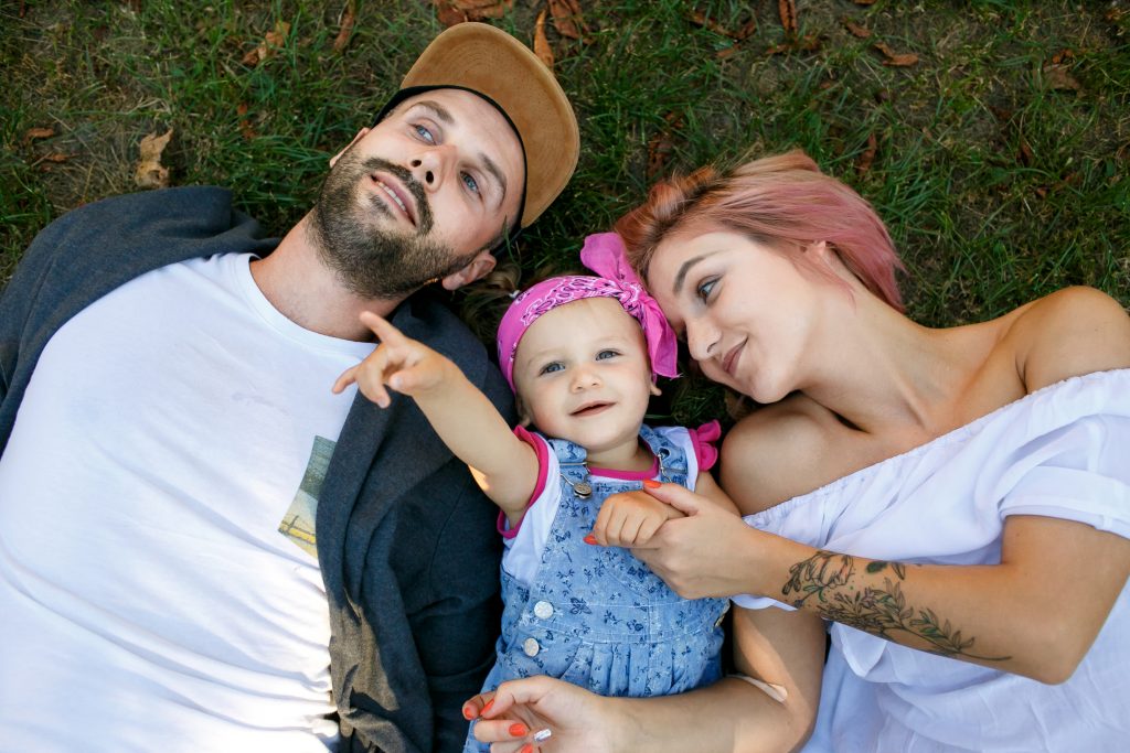 Family of three laying in the grass together.