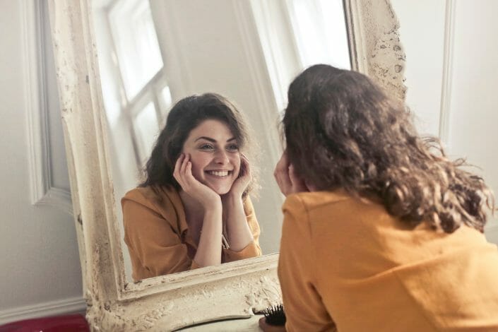 Woman in recovery looking in mirror and smiling.