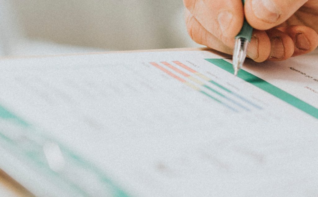 Person holding a pen and filling out a document.
