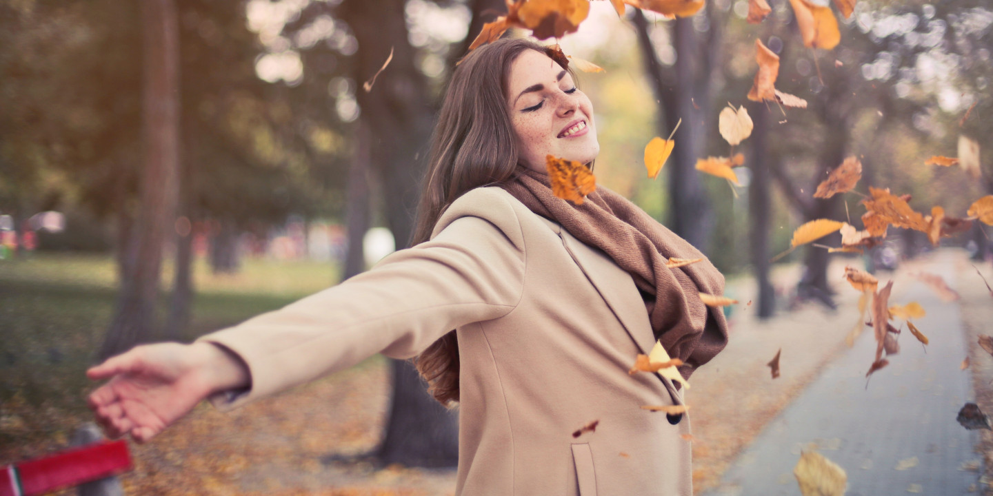 Women outside throwing fall leaves up in the air.