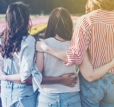 Backs of three people with their arms around one another.