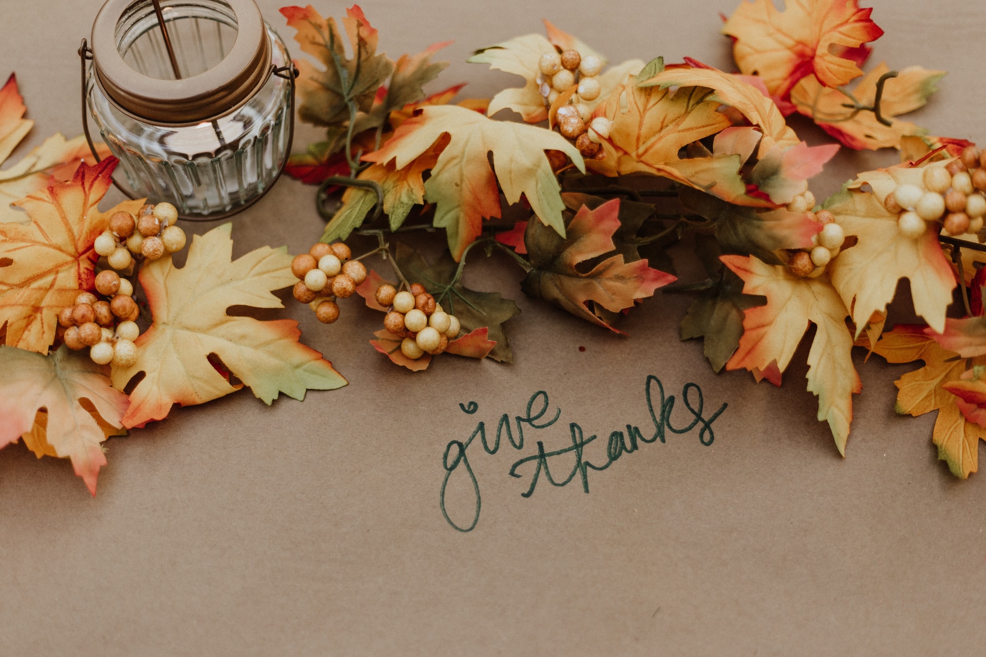 Fall leaves and candle holder on brown paper that says give thanks.