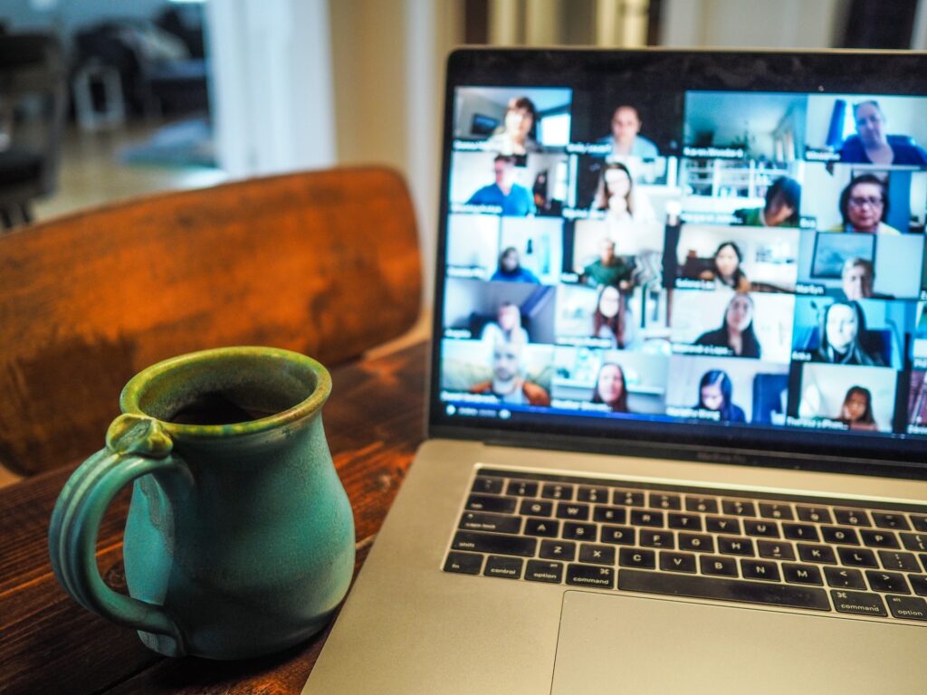 Cup of coffee next to laptop with a zoom conference call.