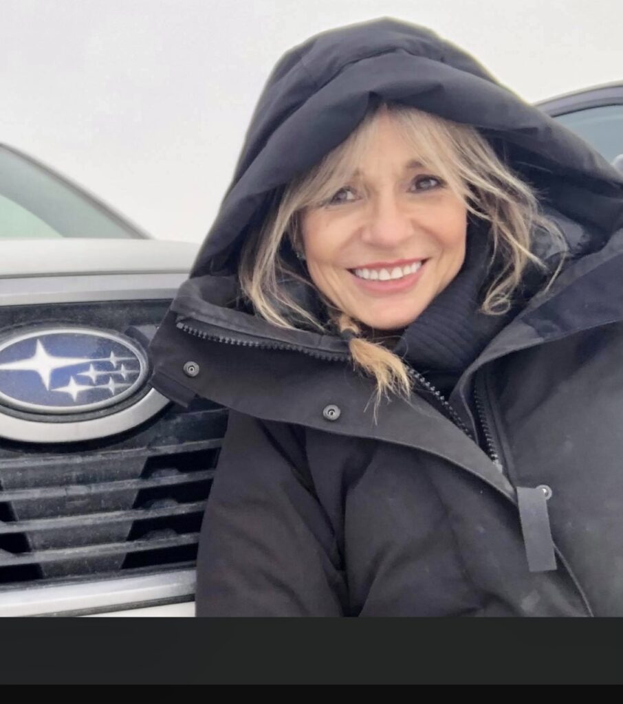 Martha Williams wearing black coat and smiling at the camera.