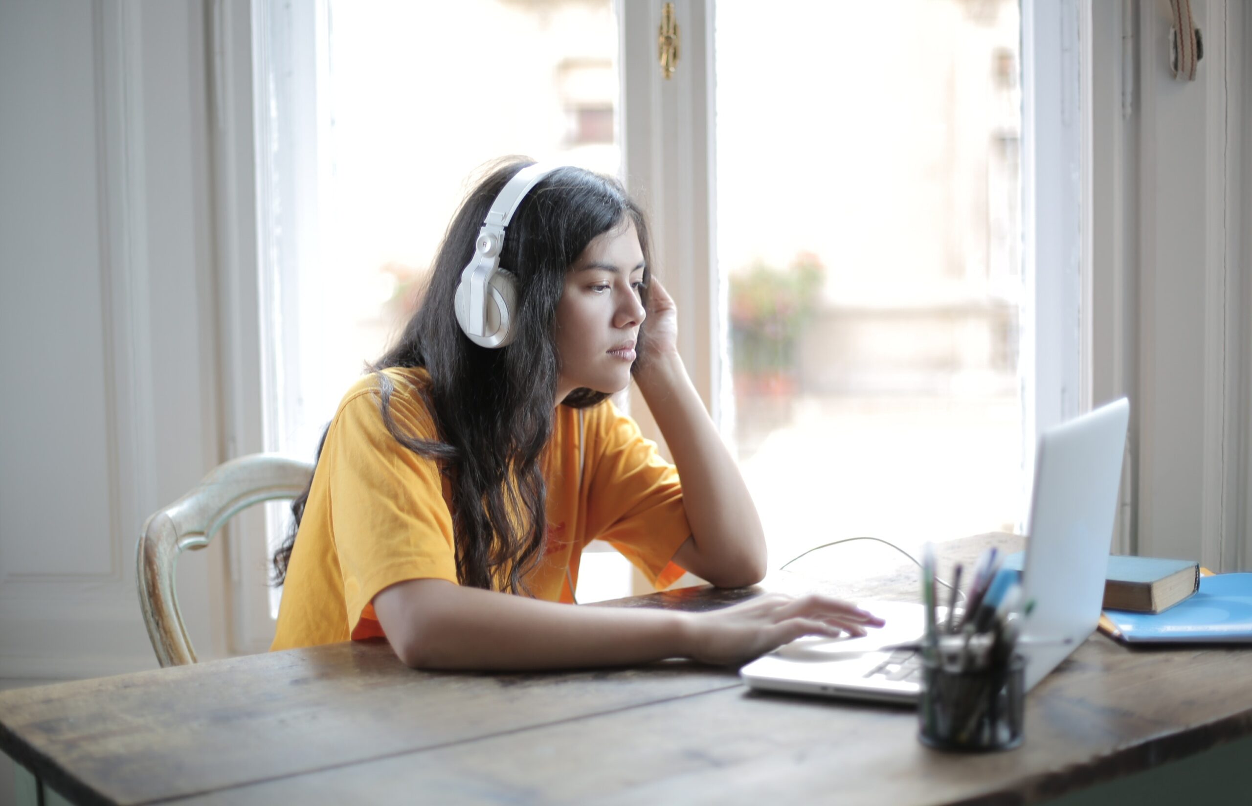 Woman working at laptop wearing headphones