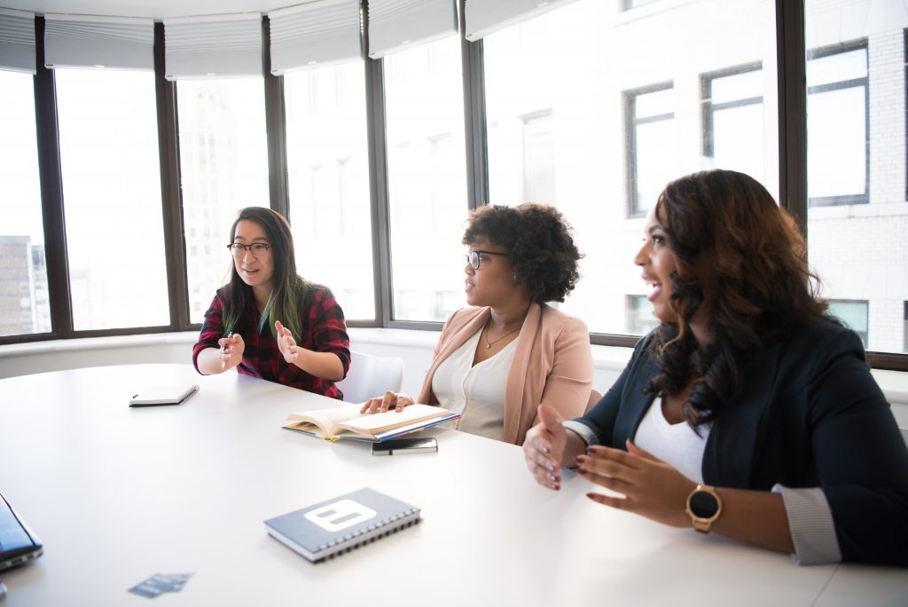 Three people sitting at boardroom table having a discussion
