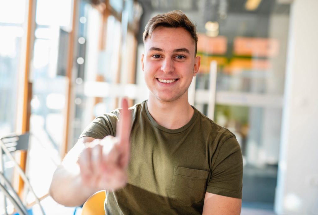 Picture of person smiling and holding up one finger