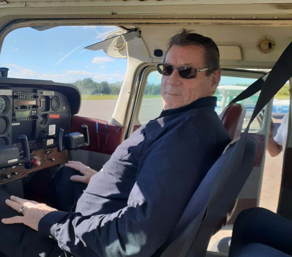 Russell, Renascent Alumni sits in an aircraft.