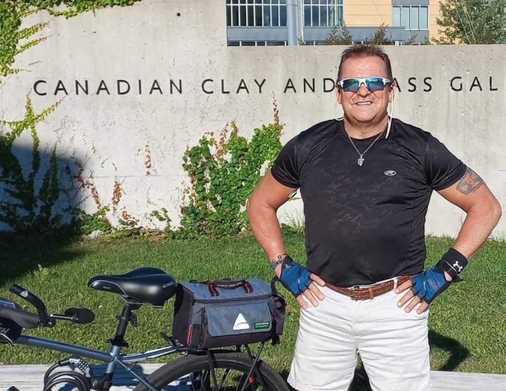 Kevin stands in front of a motorcycle.