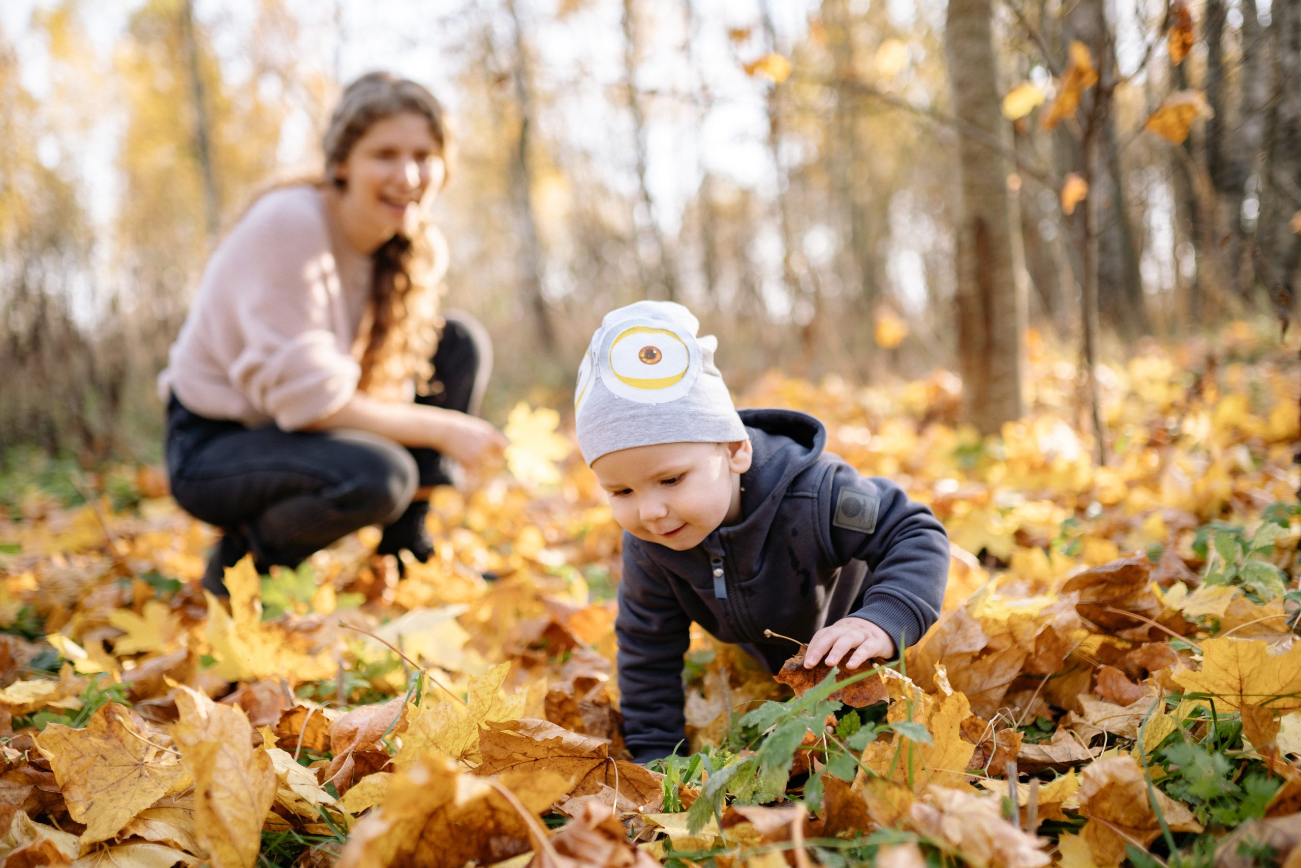 Mother playing in the leaves with child