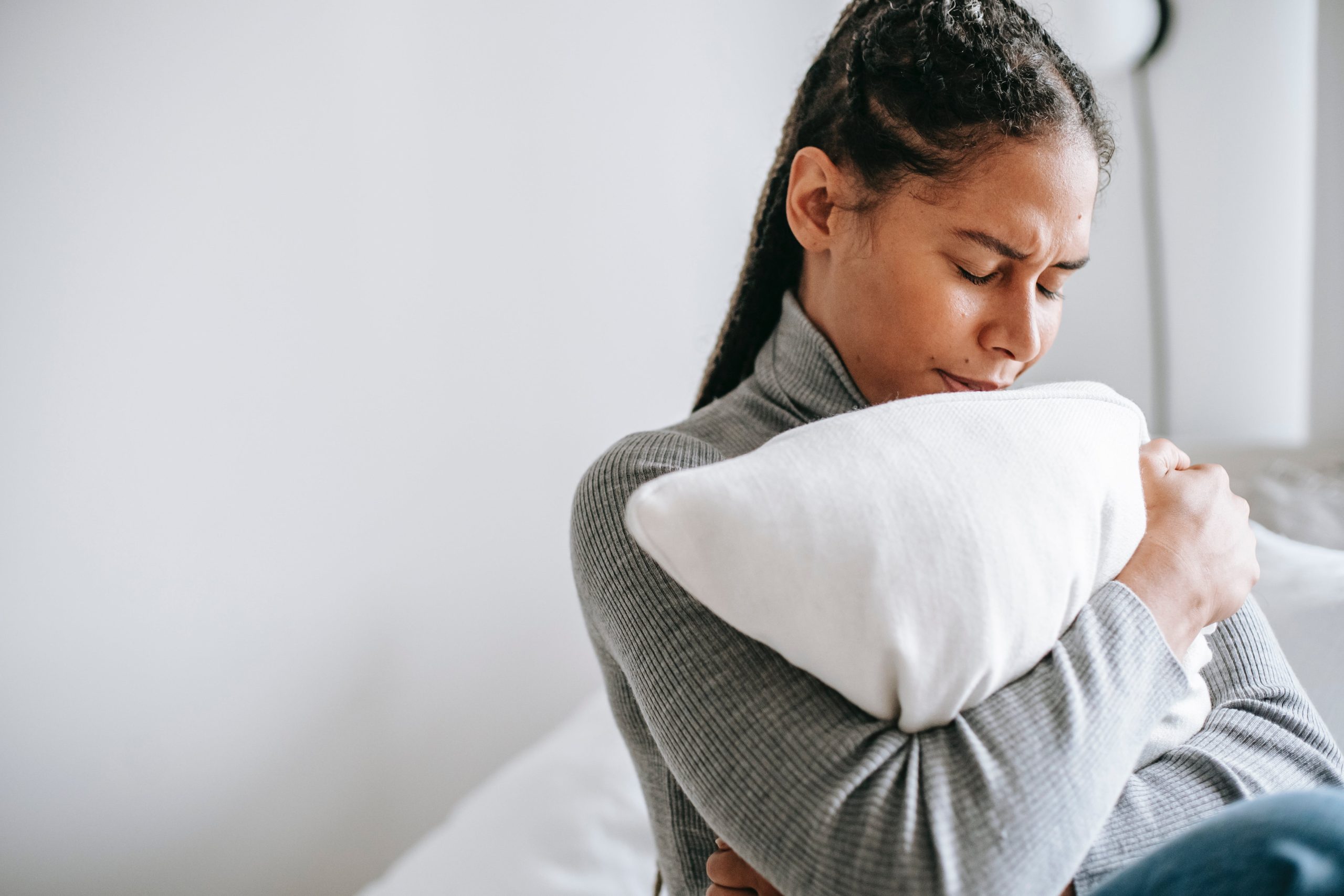 Person hugging pillow with eyes closed and head down.