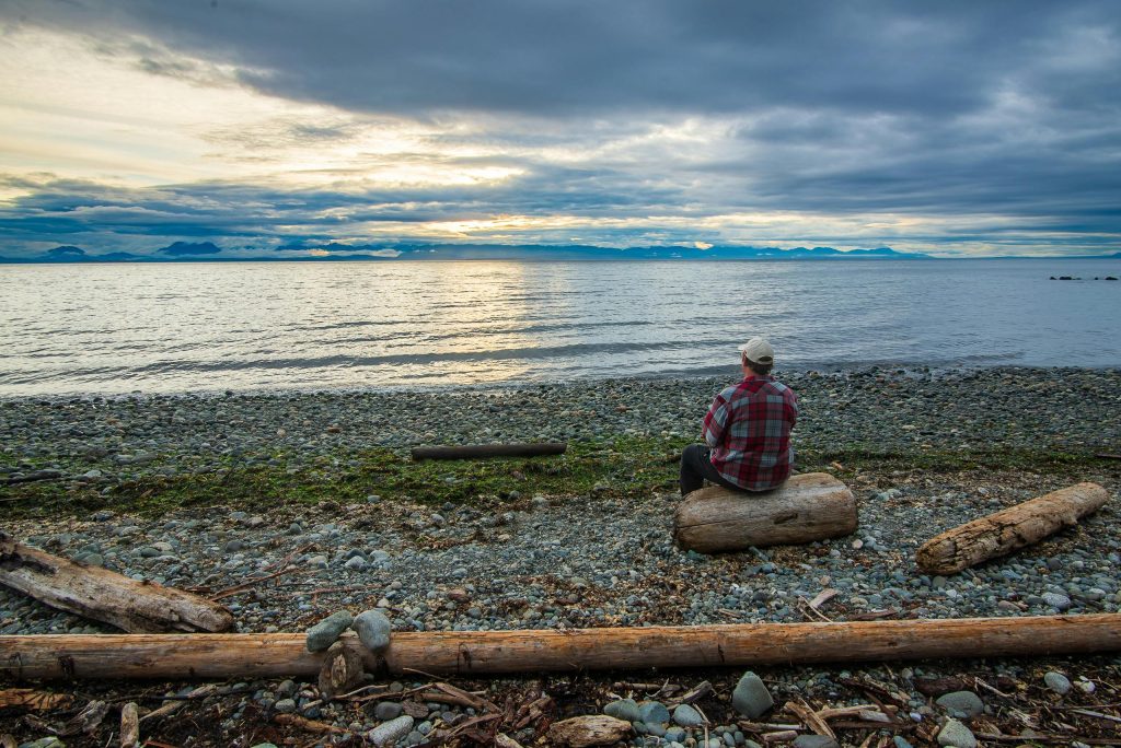 person sitting on a log by a lake