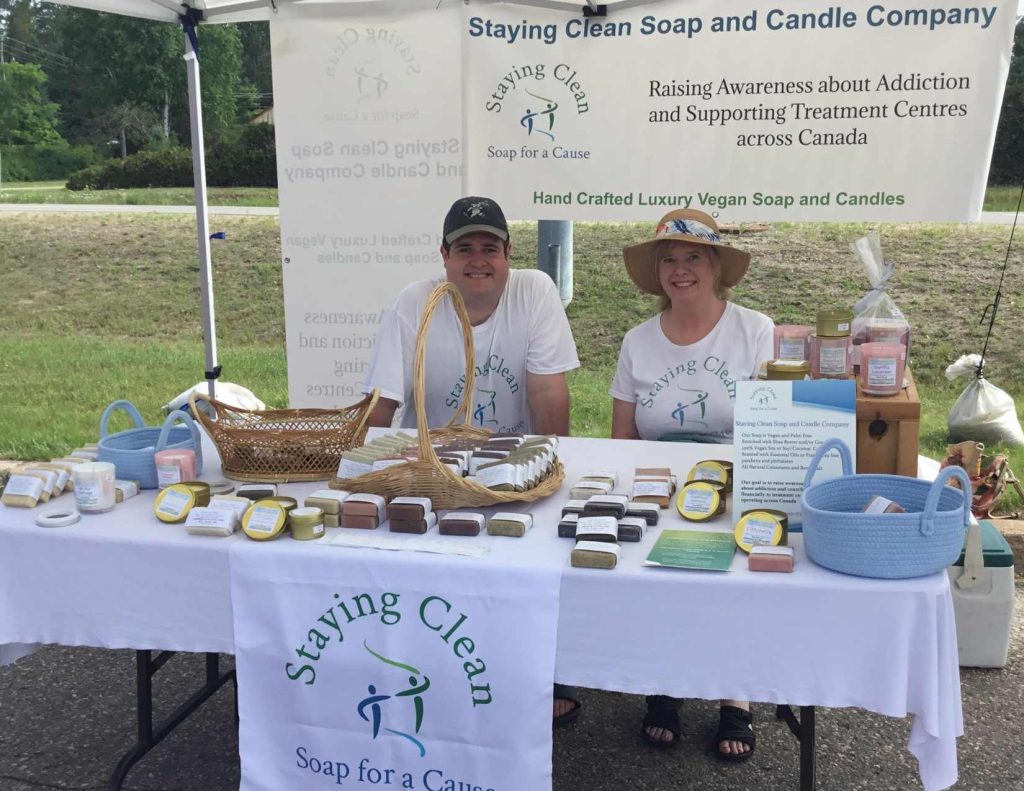 Laura and Joshua sit in front of the table for Staying Clean Soap and Candle Company.