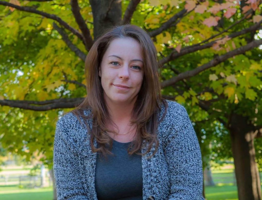 Renascent Alumni, Nancie sits at a park in the fall.