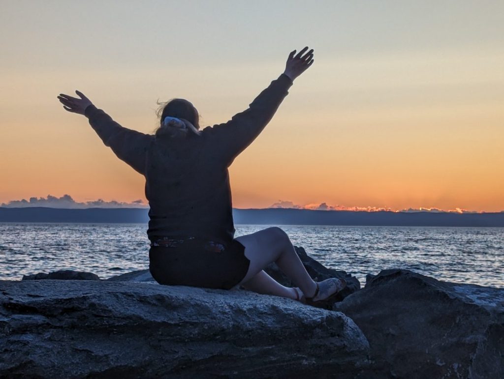 Renascent Alumni, Jenna sits on a rock.
