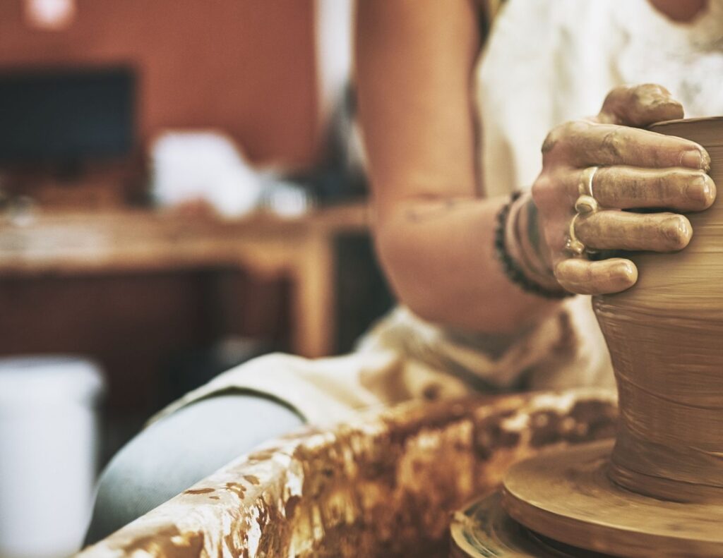 Hands molding a clay jar.